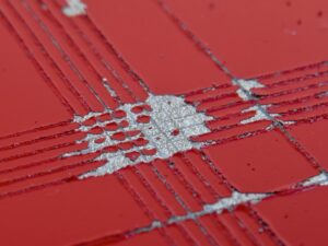 A layer of red paint on a grey substrate with cross-hatch slices to test adhesion.