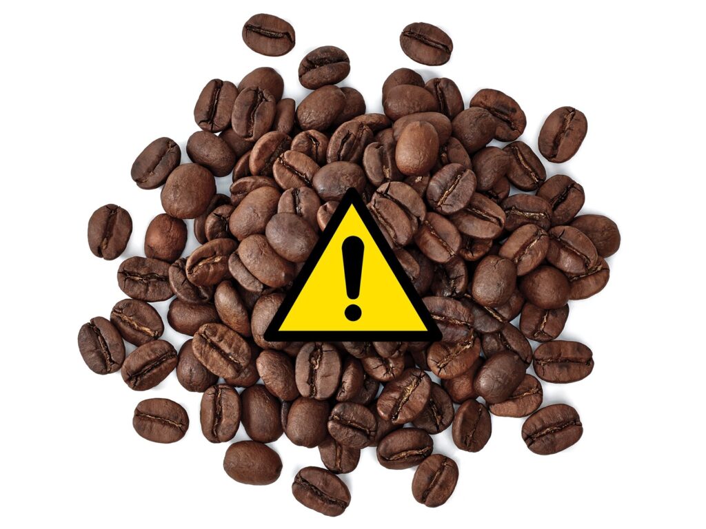 Spilled coffee beans with a triangle warning label
