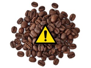 Spilled coffee beans with a triangle warning label