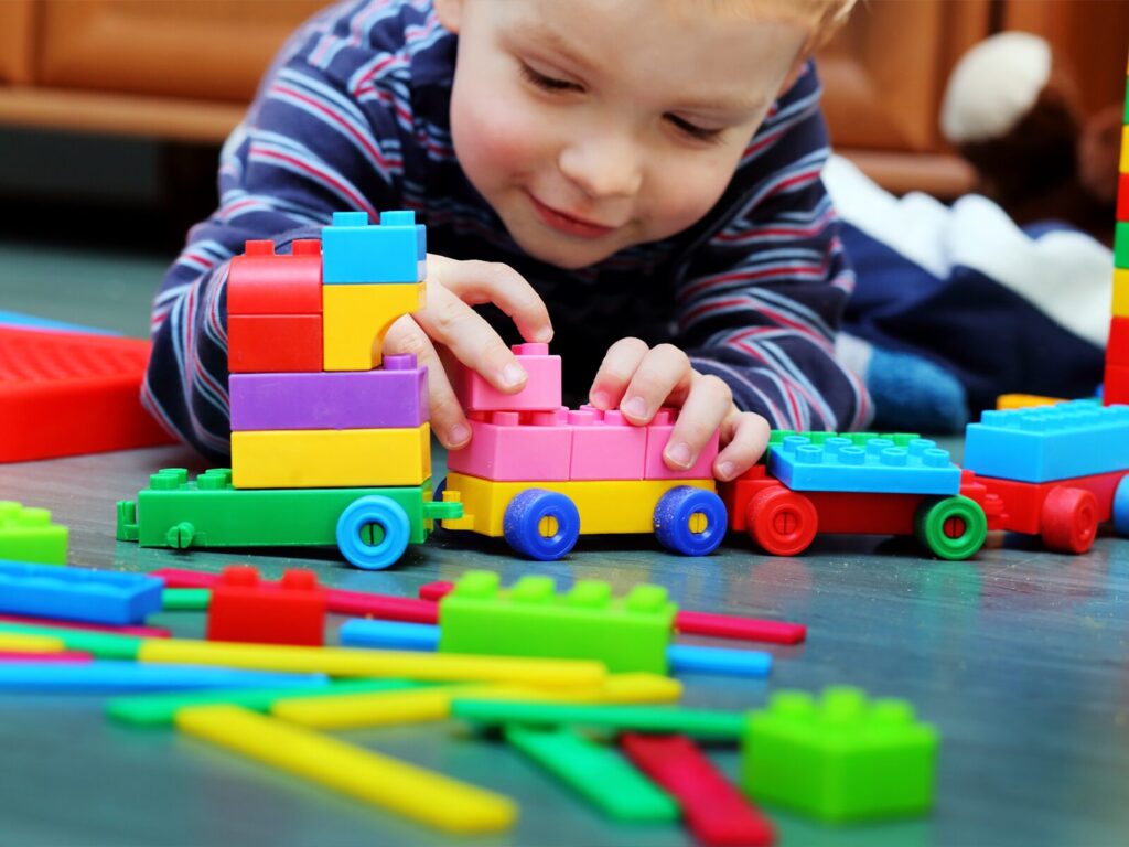 A small child plays with a colorful plastic train