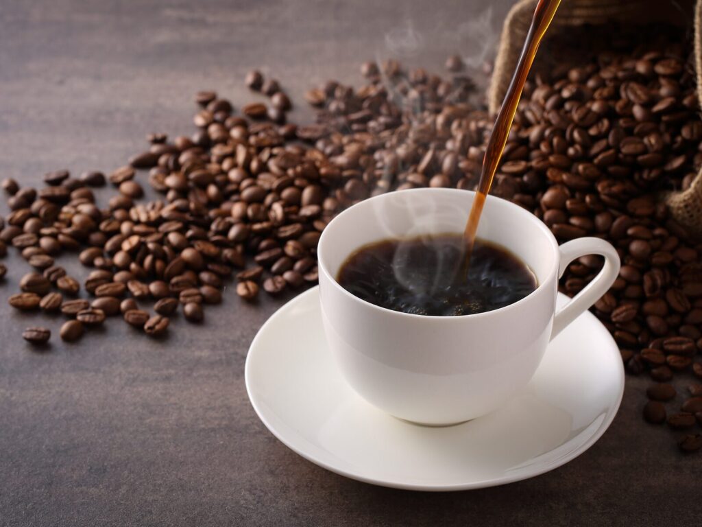 Cup of fresh coffee. Spilled coffee beans in the background.