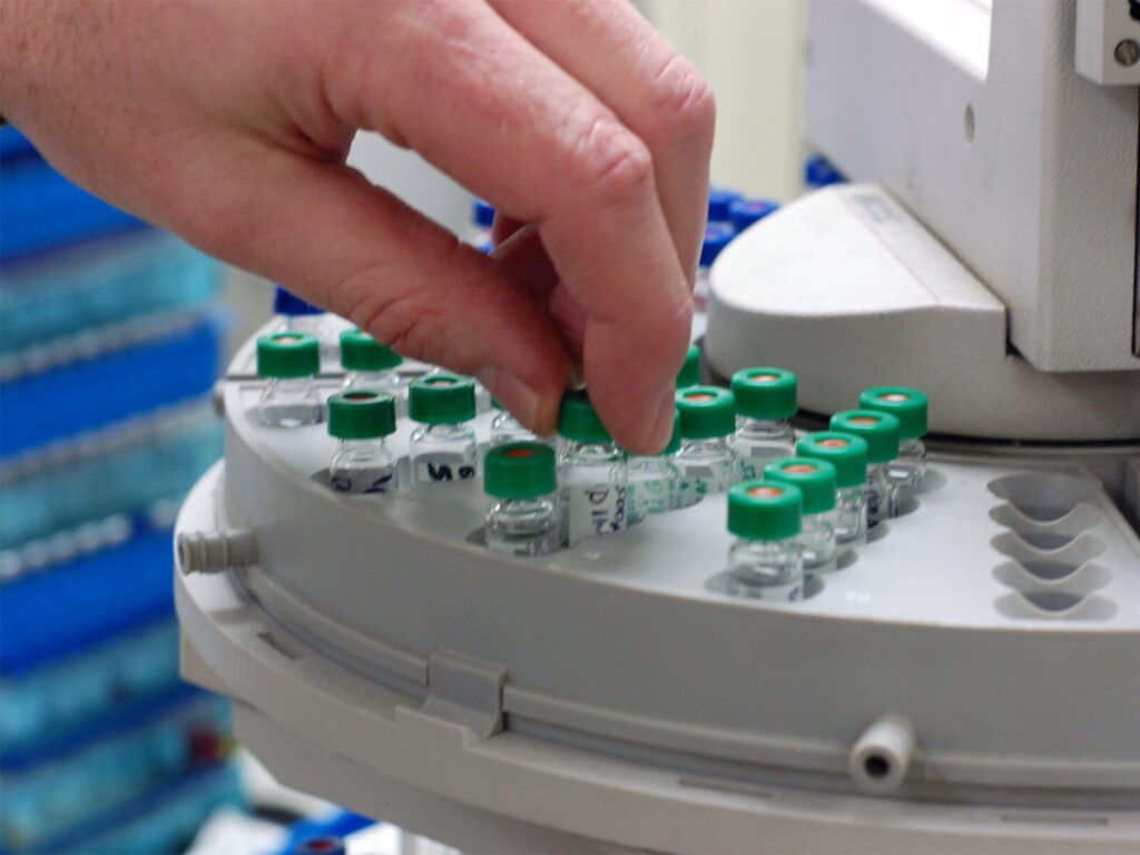 Focus on a chemist selecting a sample of chemicals for gas chromatography/mass spectroscopy.