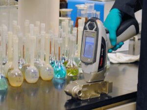 Technician scans a metal sample with a portable X-ray fluorescence (XRF) analyzer.