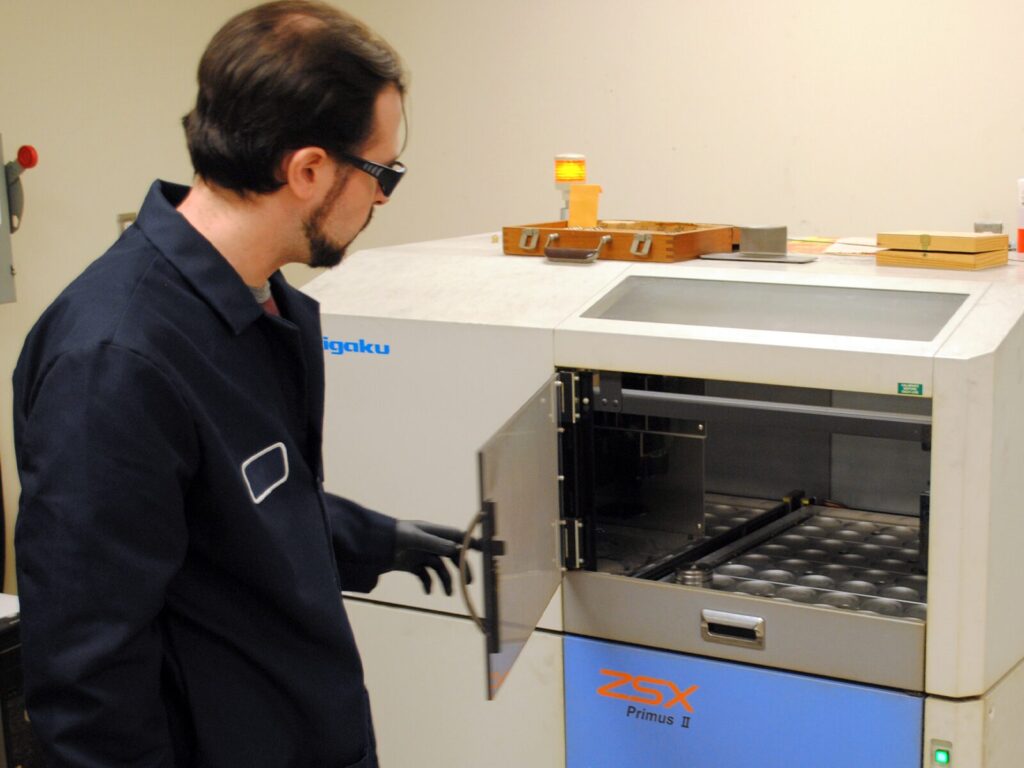 A chemist prepares a Rigaku Primus II ESX Spectrometer for wavelength dispersive X-ray fluorescence testing.