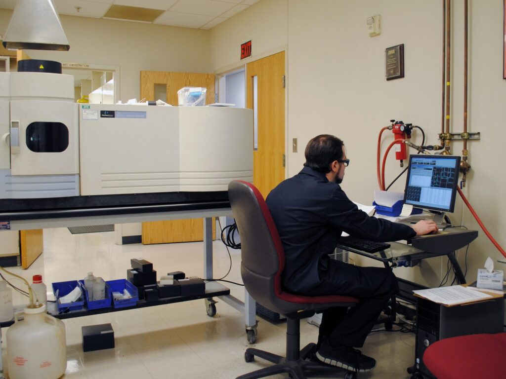 Chemist performs trace chemical analysis using Inductively Coupled Plasma (ICP).