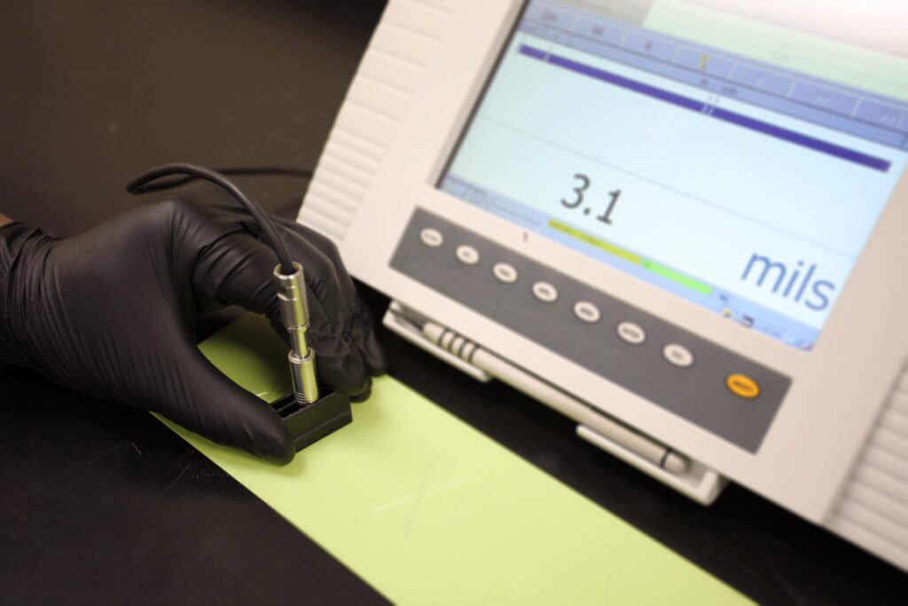 Technician performs coating thickness testing on a coat of yellow paint
