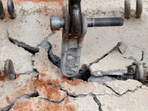 Roof anchor after failed anchor pull testing. The anchor sits atop a spider web of cracks in the concrete roof.