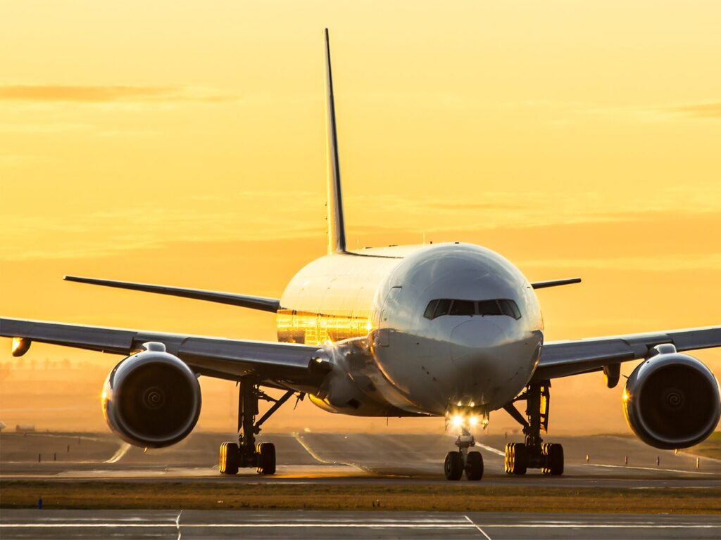 Airplane on a runway in front of a yellow sunrise