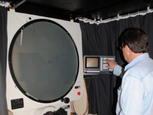 Lab technician uses an optical comparator to inspect a part
