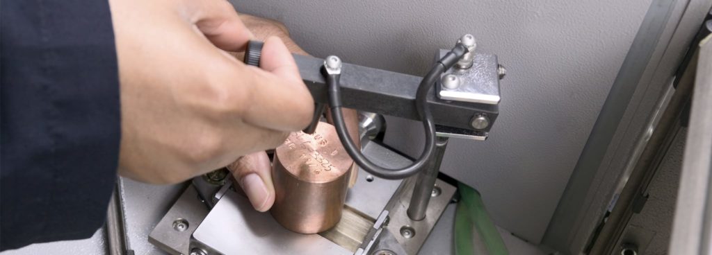 Hands performing OES Analysis on alloy sample