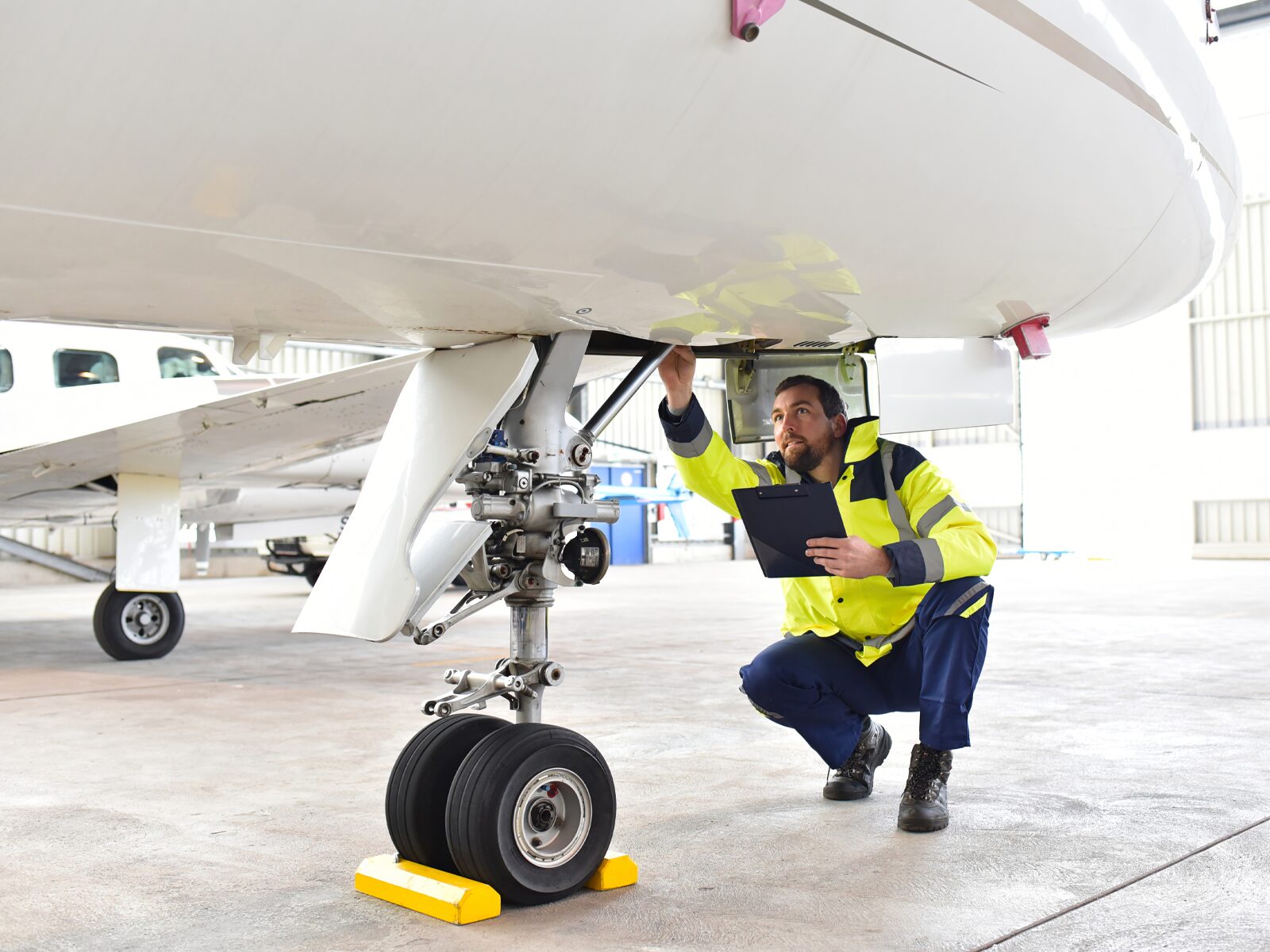 Technician inspects the undercarriage of a small plane