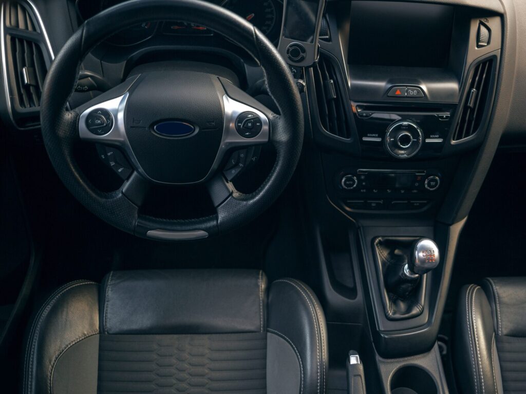 The dashboard and controls for a modern vehicle. The seats and wheel are covered in black leather.