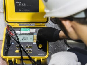 An electrical testing technician uses an insulation tester to measure insulation resistance.