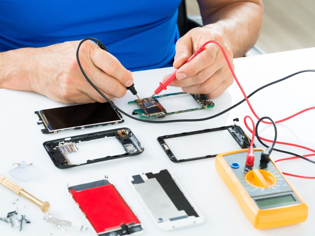 Technician uses a multimeter to test the disassembled parts of a smart phone.
