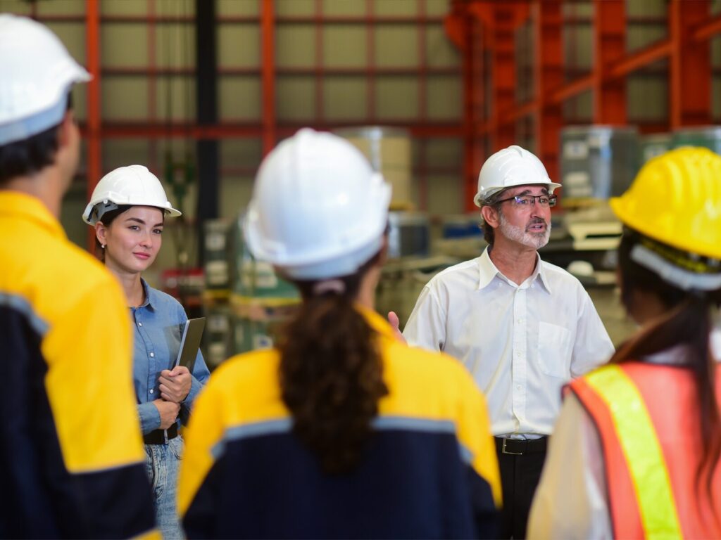 Two experts address a team of engineers at an industrial plant