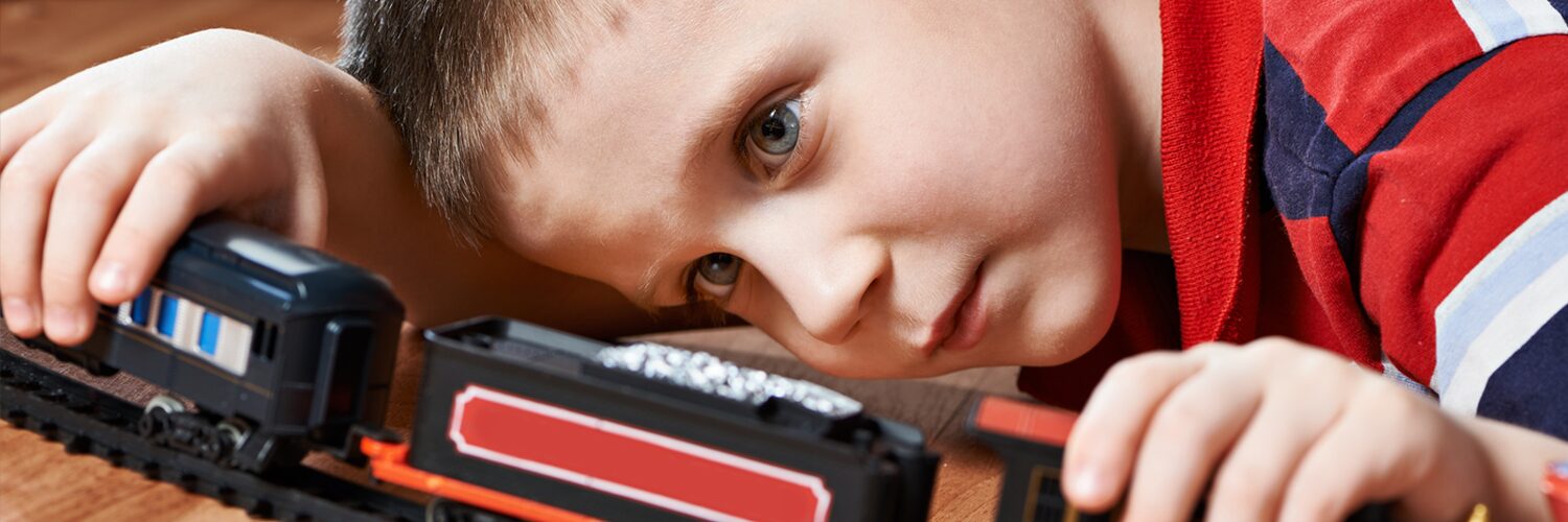 Young boy plays with a model train set