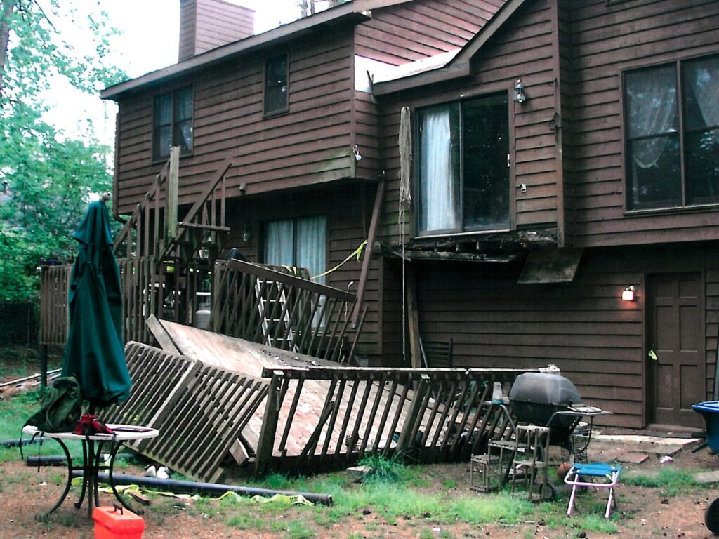The back view of a house with a collapsed deck.
