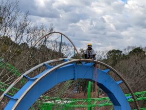A rope access technician on top of a roller coaster