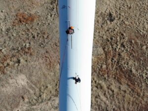 Two rope access technicians ascend a wind turbine tower