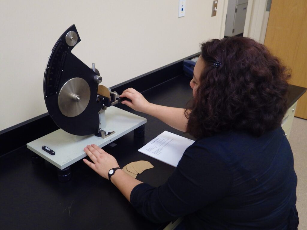 Lab technician prepares a pendulum for an Elmendorf tear test.
