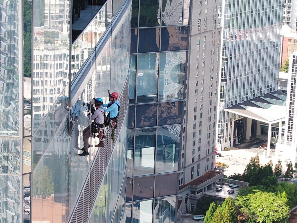 Two rope access technicians suspended alongside a commercial office building