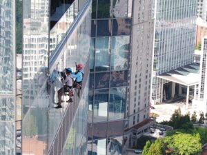 Two rope access technicians suspended alongside a commercial office building