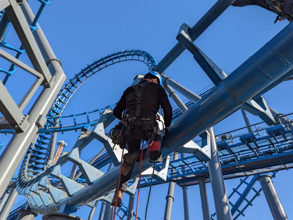 Rope access technician examines a vertical loop rollercoaster.