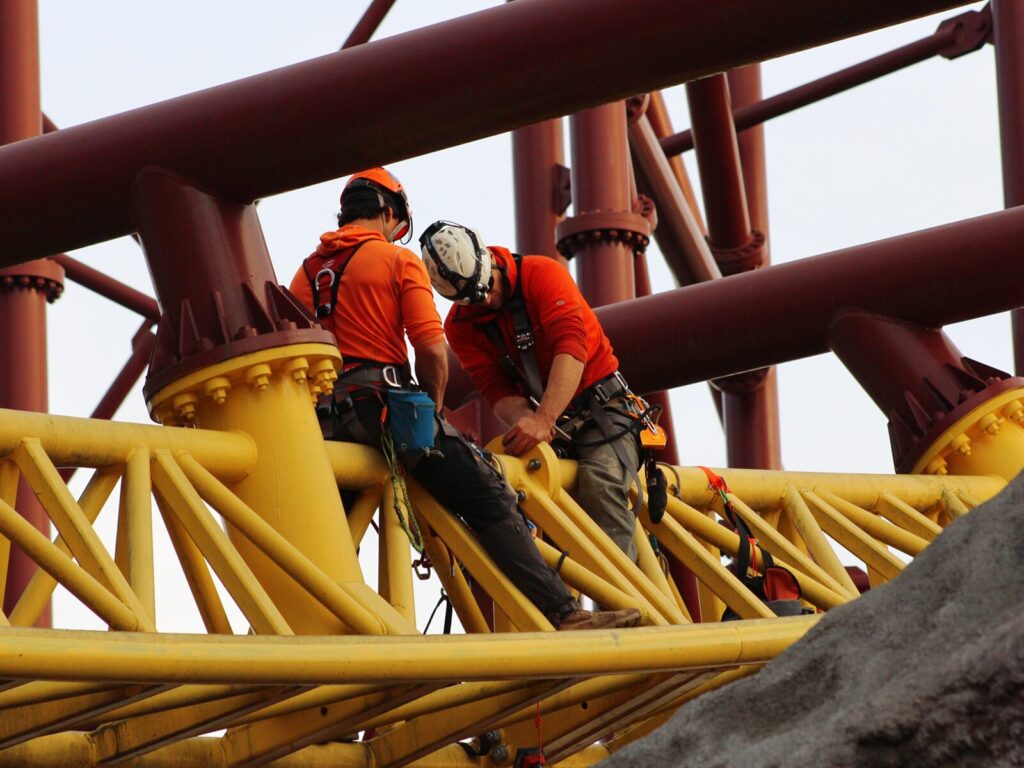 Two rope access technicians inspect the bolts on an amusement ride