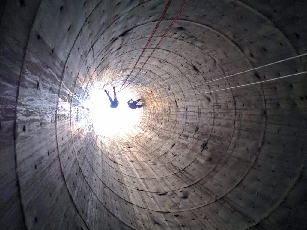 Ground view of two rope access technicians descending the inside of an industrial tower