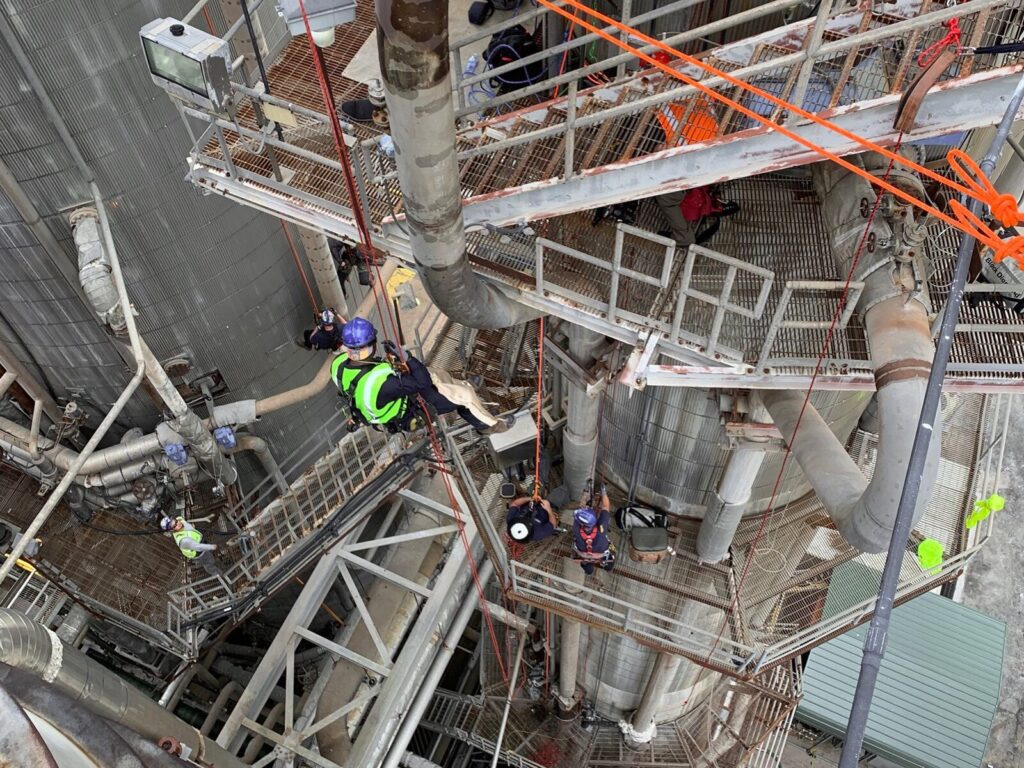 Multiple rope access technicians suspended via anchor system at a power generation site
