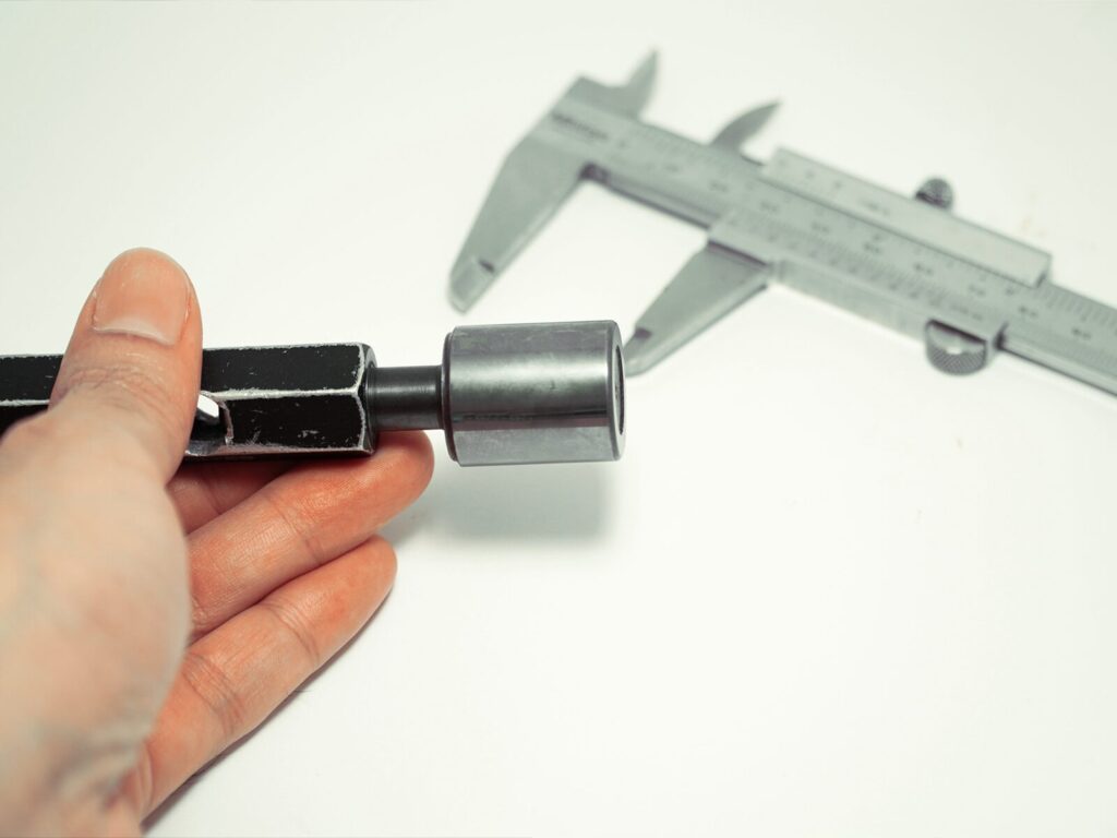 Technician holds a plug gauge. A Vernier caliper is in the background.