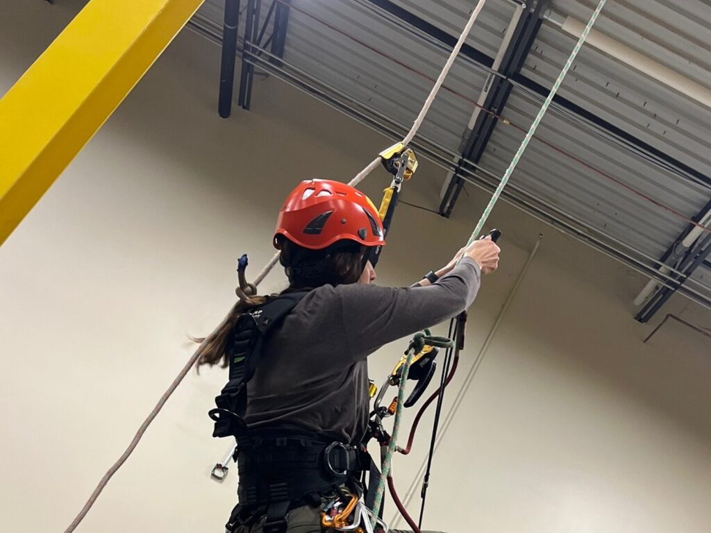 Rope access technician adjusts her ascender on a rope training course