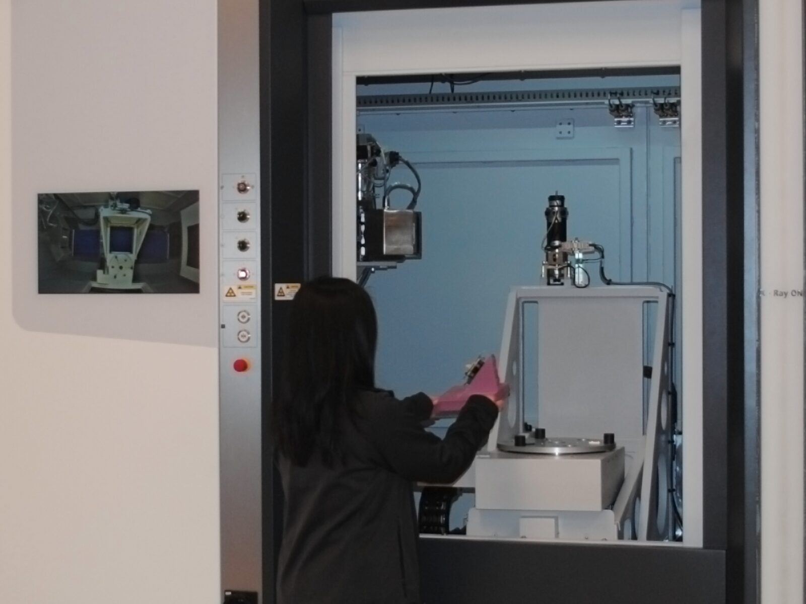 Technician loads a pink component into a computed tomography X-ray machine.