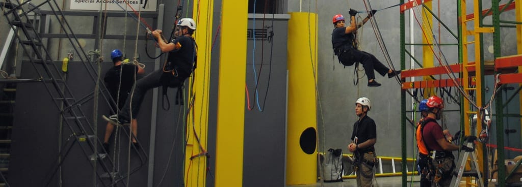 Instructor Looks on as Students Navigate Rope Systems