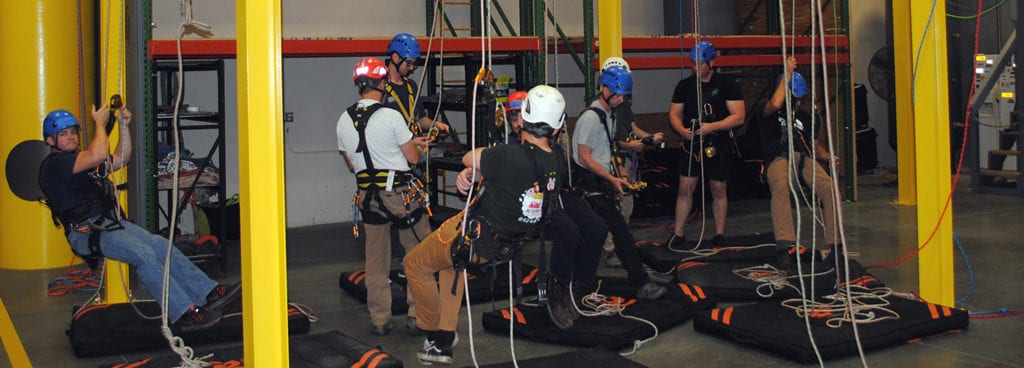 Instructor Helping Student Secure His Line as Others Prepare to Ascend