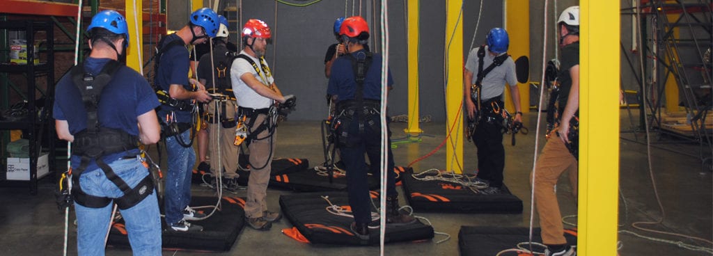 Instructor Showing Students Proper Method of Securing Harness to Rope Line