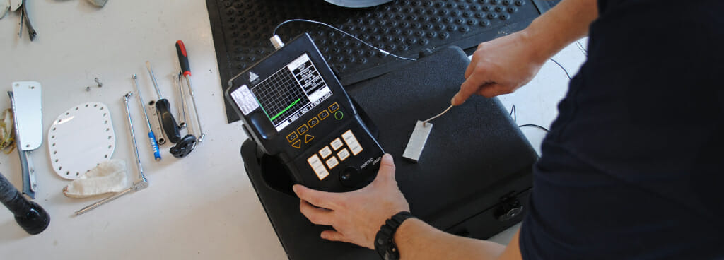 technician uses eddy current inspection tool to inspect aircraft component