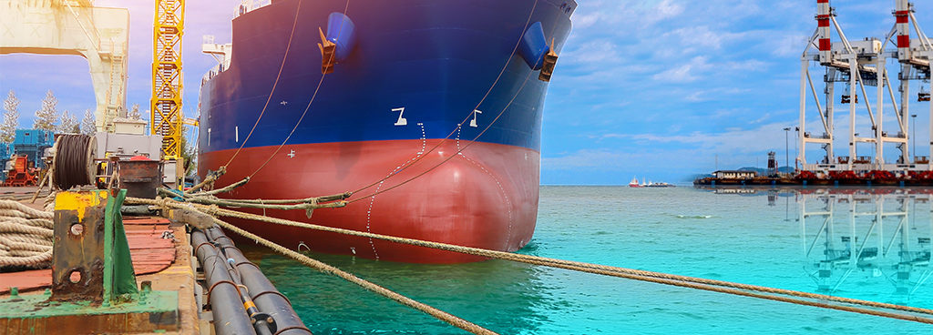 Hull of large red and blue ship tied down to port