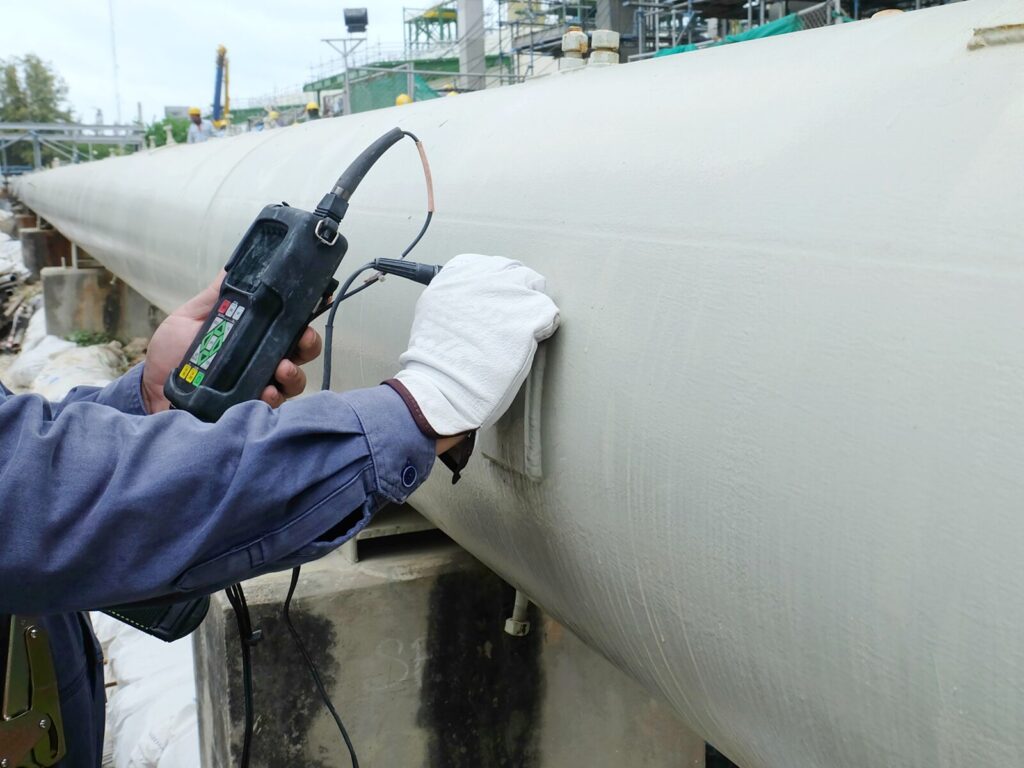 NDT technician holds an ultrasonic probe to a pipeline for ultrasonic testing