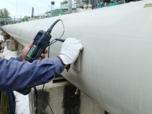 NDT technician holds an ultrasonic probe to a pipeline for ultrasonic testing