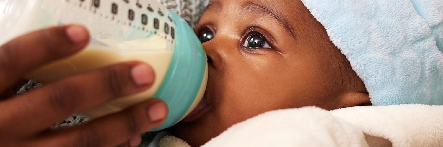 Small baby drinks from a baby bottle