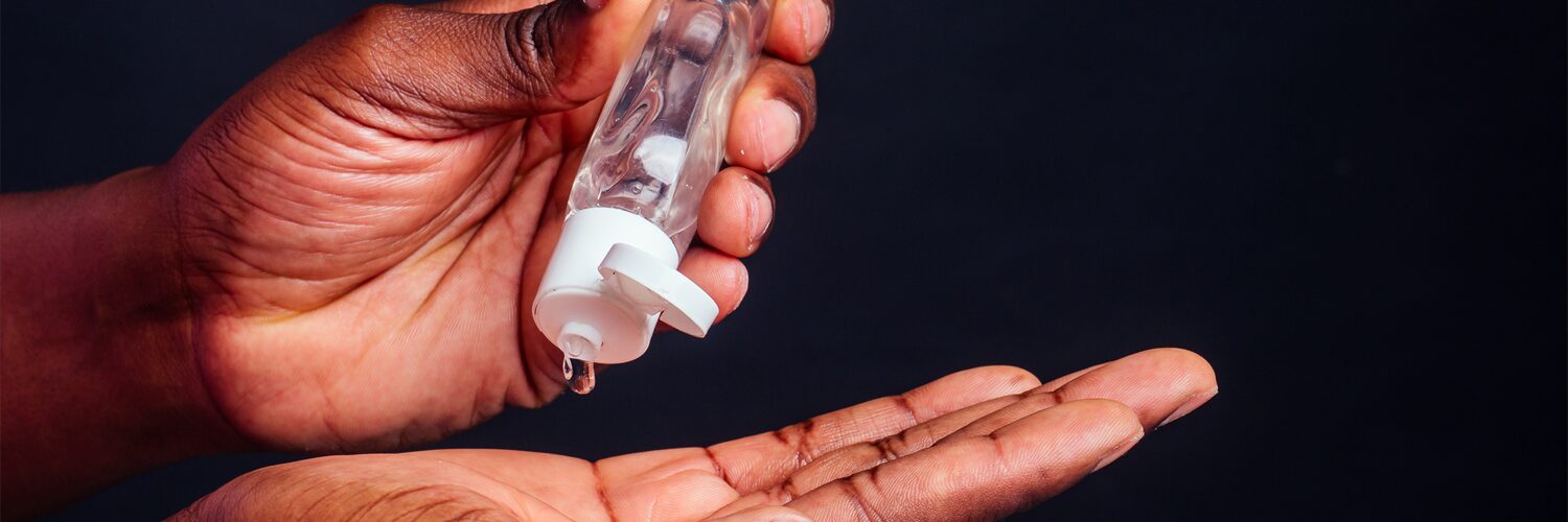 Hand squeezes a small bottle of hand sanitizer