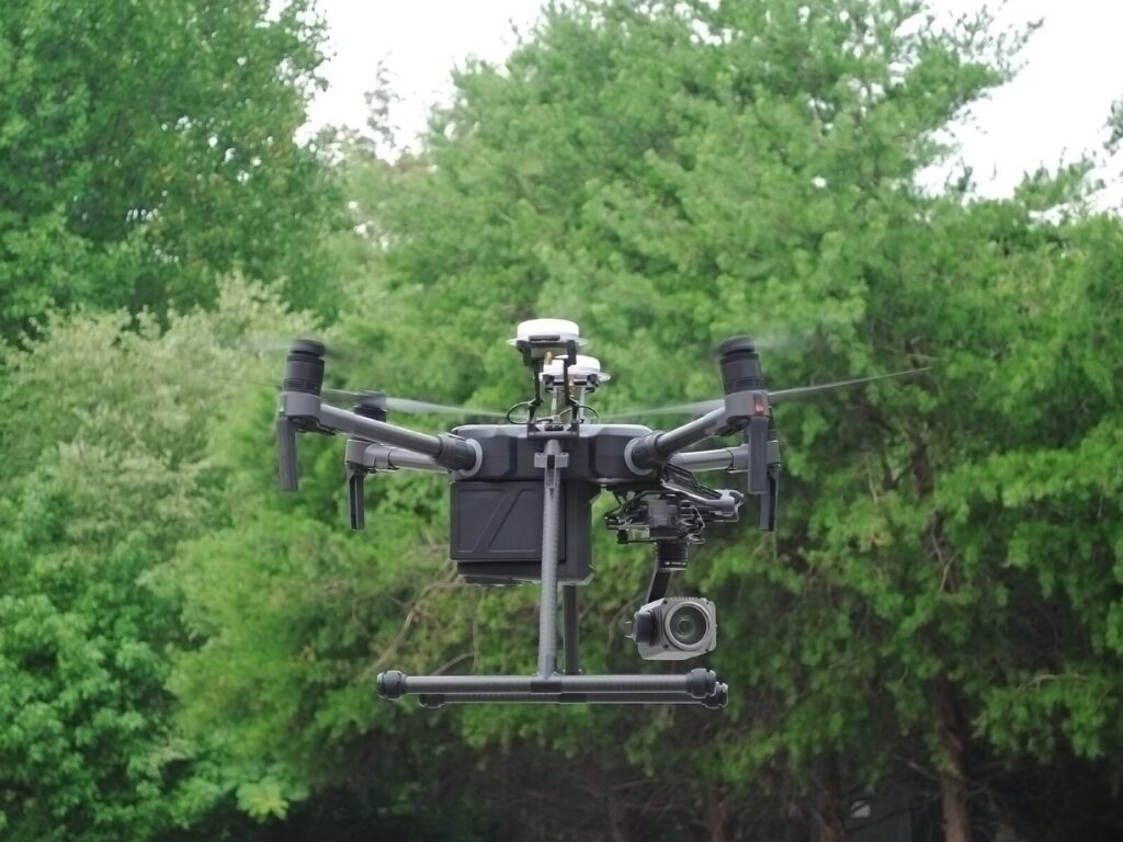 Unmanned aerial vehicle, or drone, hovers in front of trees