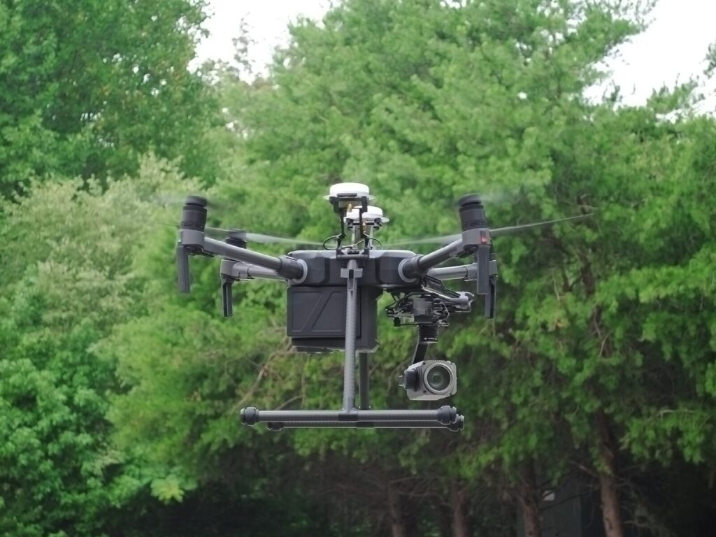 Unmanned aerial vehicle (drone) hovers in front of trees