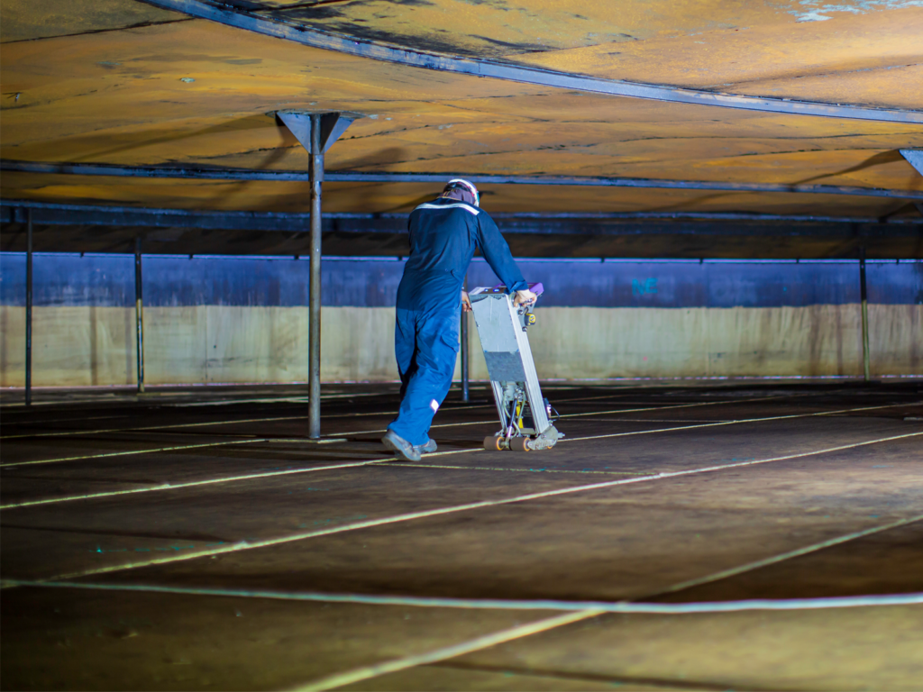 Technician performing tank floor inspection