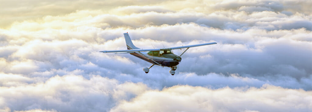 Stock Photo of Small Private Aircraft Above the Clouds
