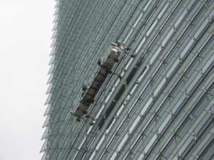 Window washers suspended in front of an office building.