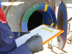 Technician with a clipboard inspects the main hole to an aboveground tank.
