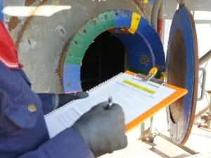 Technician with a clipboard inspects the main hole to an aboveground tank.