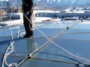 Rope access technician inspects a rope anchored to a commercial building rooftop